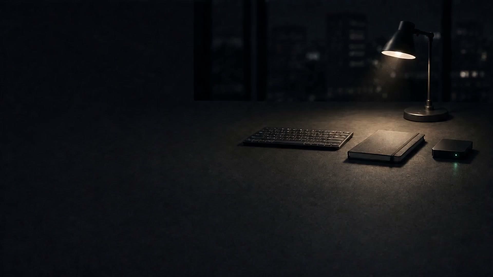 A dim night operations desk: a keyboard, a notebook and a small device with one green status light under a warm desk lamp, a round wall clock above and a dark city skyline in the window.